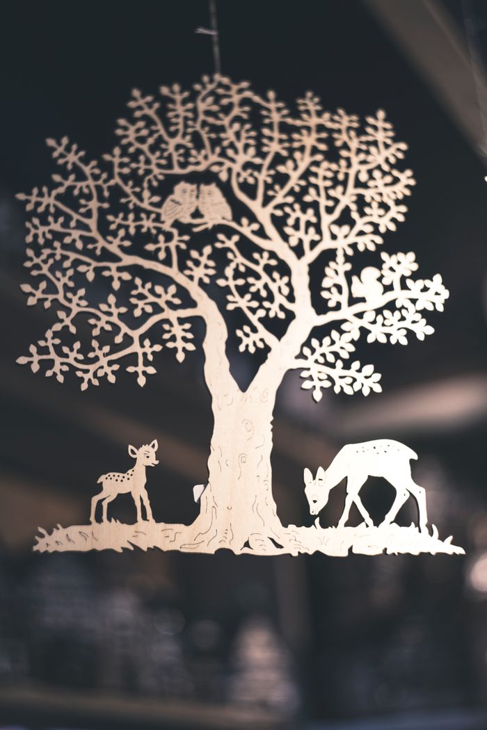 Intricate paper cut silhouette of a tree with deer, creating a stunning artistic design.