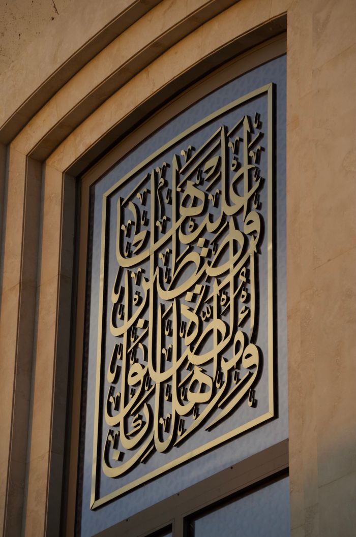 Intricate Arabic calligraphy decorates the frame of a mosque window in an artistic display.
