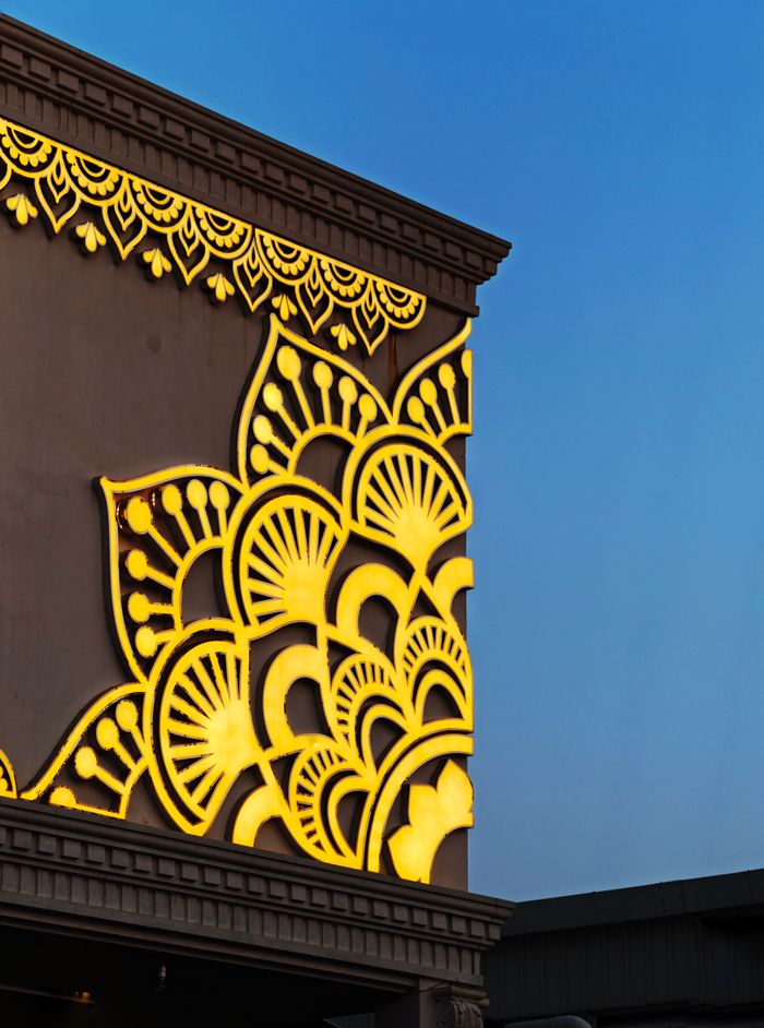 A decorative wall with intricate illuminated patterns against a twilight sky, showcasing modern design.